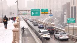 People walk along the Brooklyn Bridge as cars drive into Manhattan on January 6 in New York City.