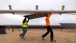 Workers install solar panels for the Los Angeles Department of Water and Power's biggest solar and battery storage plant, the Eland Solar and Storage Center in the Mojave Desert of Kern County, on November 25, 2024, near California City, California.