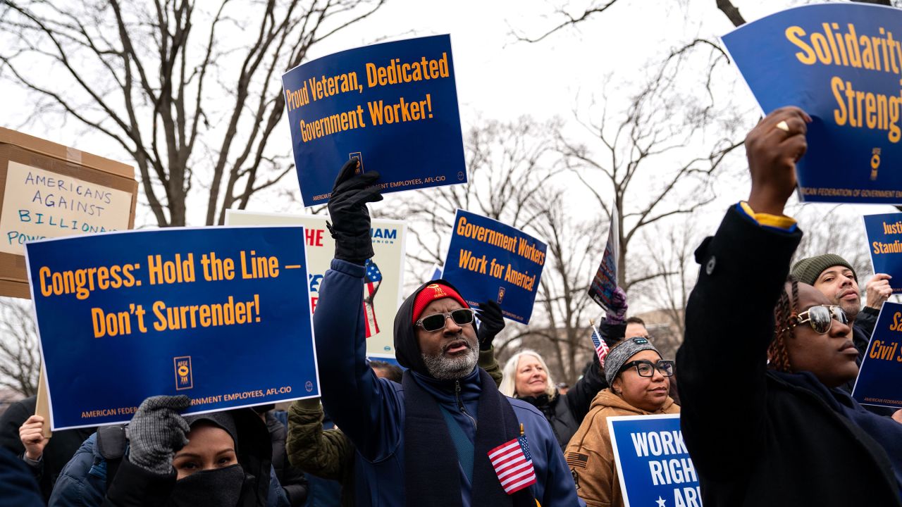 People hold signs as they gather for a "Save the Civil Service" rally hosted by a federal employee union outside the US Capitol on February 11 in Washington, DC.