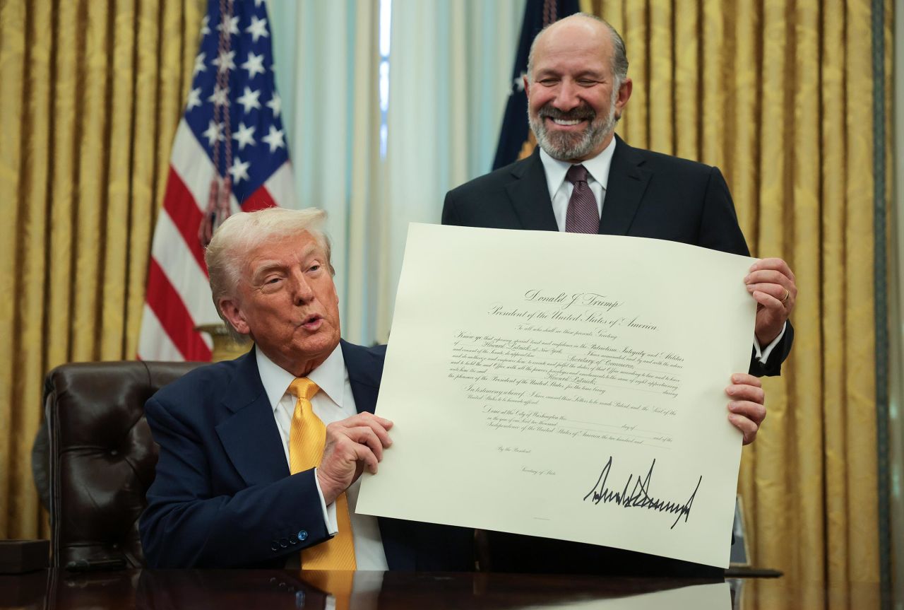 President Donald Trump and Commerce Secretary Howard Lutnick hold Lutnick's commission after he was sworn in as Commerce Secretary in the Oval Office at the White House on February 21, in Washington, DC. 