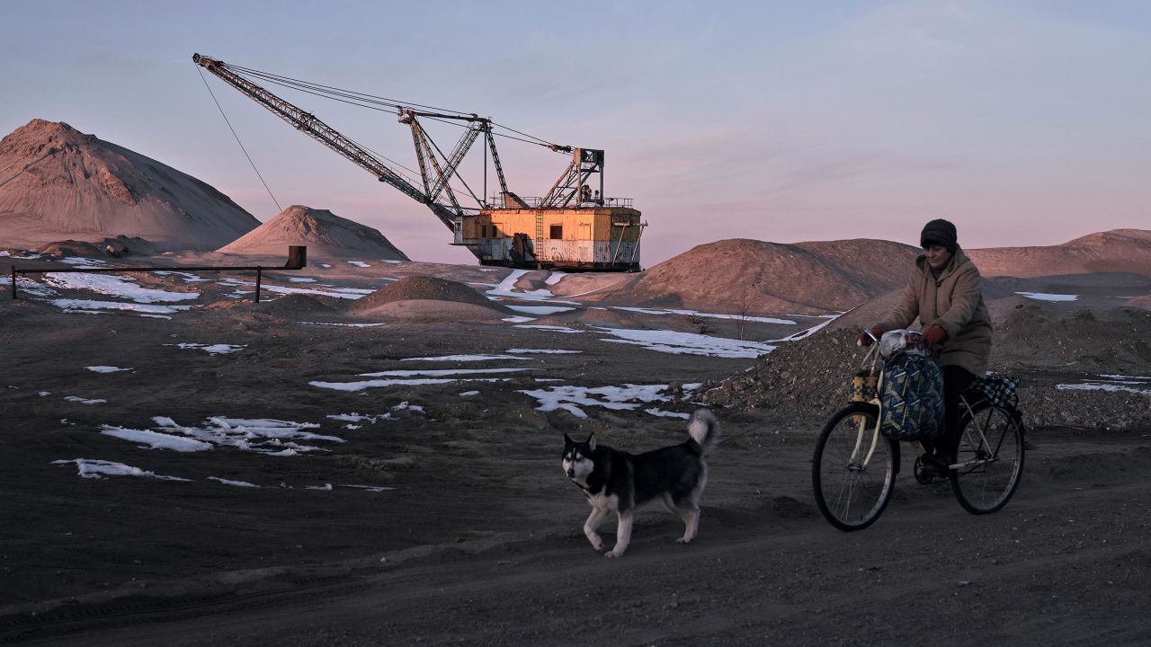 A woman cycles past with her dog as an excavator mines on February 25, in the Zhytomyr region of Ukraine. 