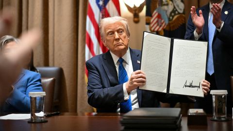 President Donald Trump displays an executive order after signing it during a meeting with US Ambassadors in the Cabinet Room of the White House in Washington, DC, on March 25, 2025.