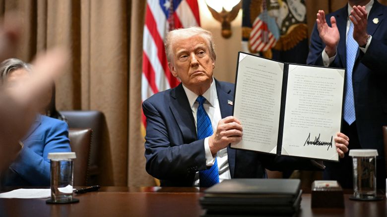 President Donald Trump displays an executive order after signing it during a meeting with US Ambassadors in the Cabinet Room of the White House in Washington, DC, on March 25, 2025.