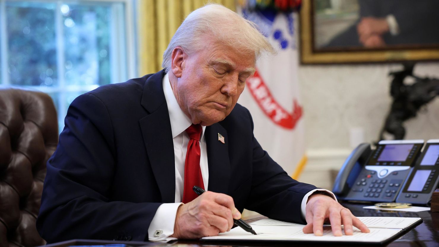 President Donald Trump signs an executive order in the Oval Office of the White House on March 26, in Washington, DC.
