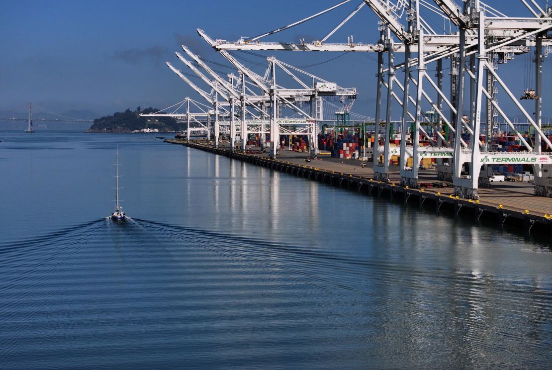 A sailboat passes idle shipping cranes at the Port of Oakland on April 28 in Oakland, California.