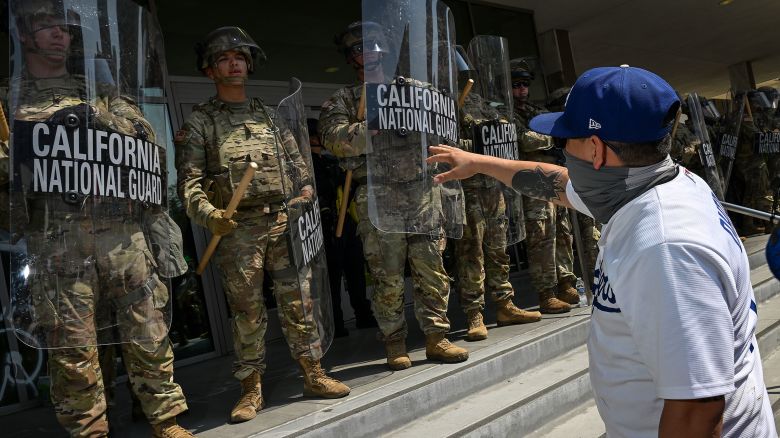 Members of the California National Guard watch as protesters are seen outside the Metropolitan Detention Center on June 9 in Los Angeles.