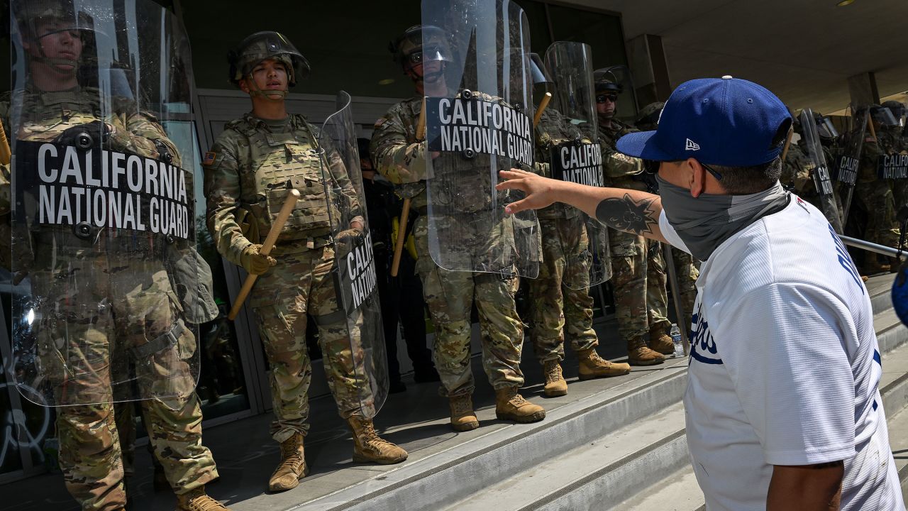Members of the California National Guard watch as protesters are seen outside the Metropolitan Detention Center on June 9 in Los Angeles.