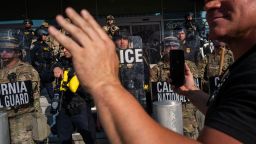 A person holds up their phone in front of the National Guard and police as they confront protesters following three days of clashes with police after a series of immigration raids on June 9, in Los Angeles.