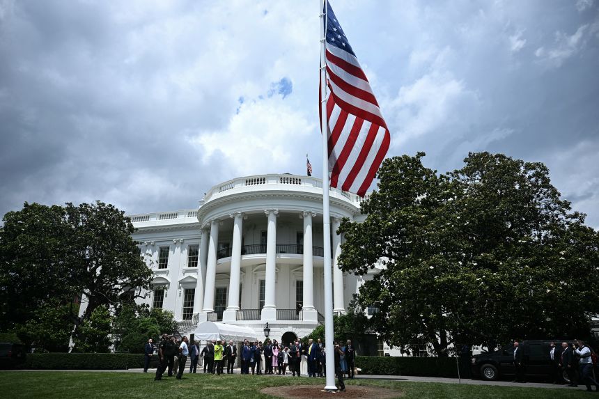 President Donald Trump looks on as a US flag is raised on a newly installed flagpole on the South Lawn of the White House in Washington, DC on June 18. 