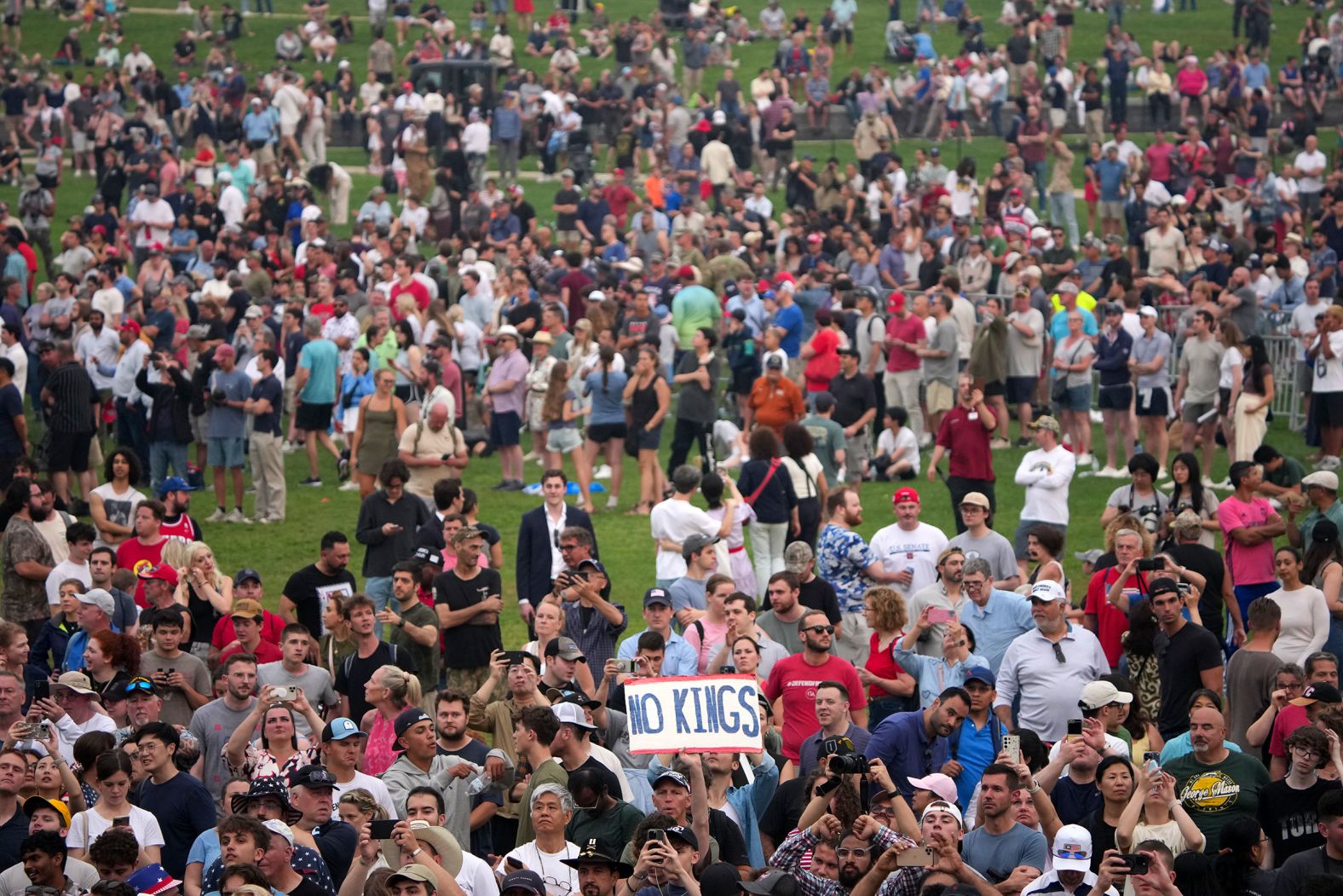 A protestor holds a "No Kings" as he stands among people watching the parade from the National Mall. More than 2,000 <a href="index.php?page=&url=https%3A%2F%2Fwww.cnn.com%2F2025%2F06%2F14%2Fus%2Fgallery%2Fno-kings-protests">protests</a> were scheduled across all 50 states Saturday through the No Kings movement, which organizers say seeks to reject “authoritarianism, billionaire-first politics, and the militarization of our democracy.”