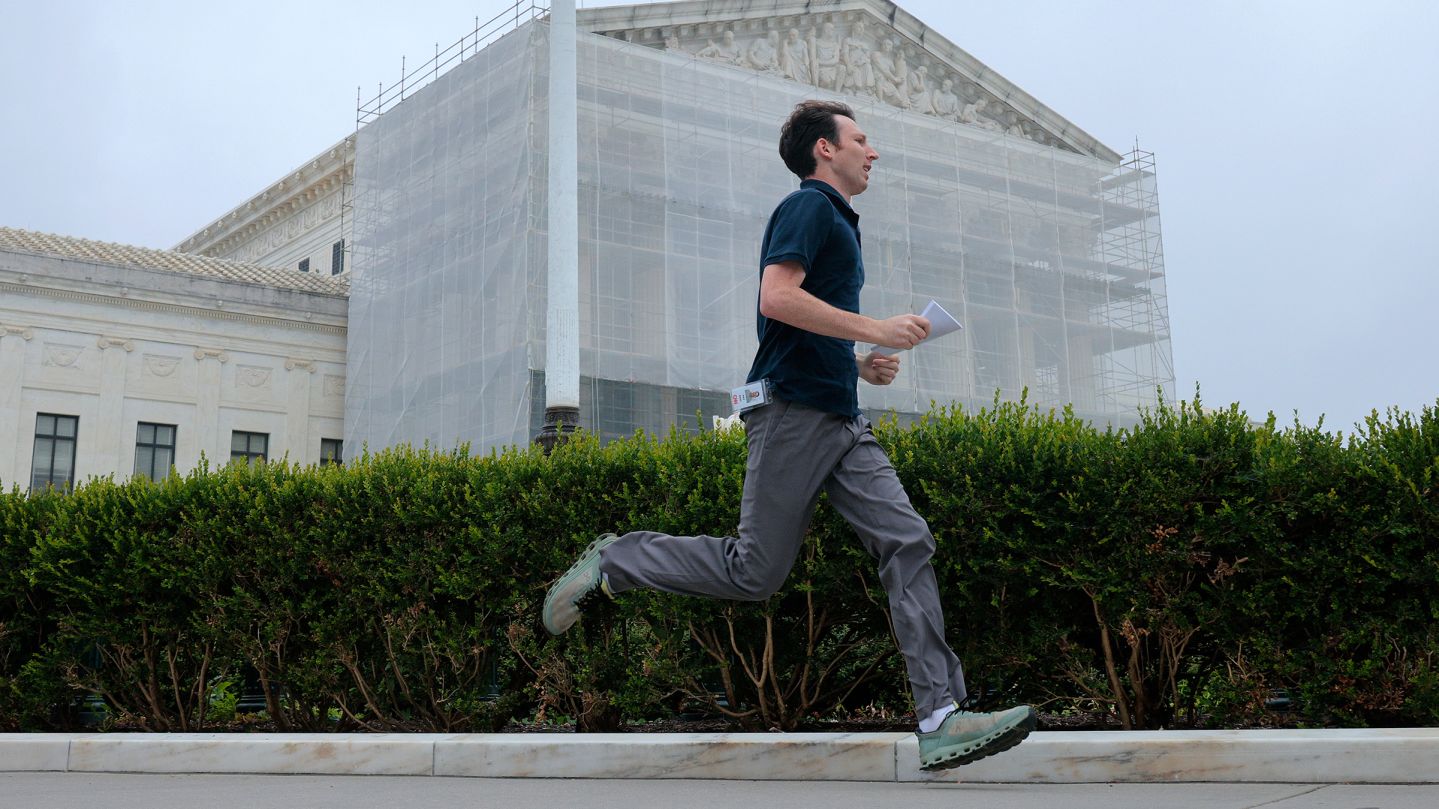 CNN's Max Rego runs out of the US Supreme Court building carrying an ruling during the last day of the court's term on June 27, in Washington, DC.