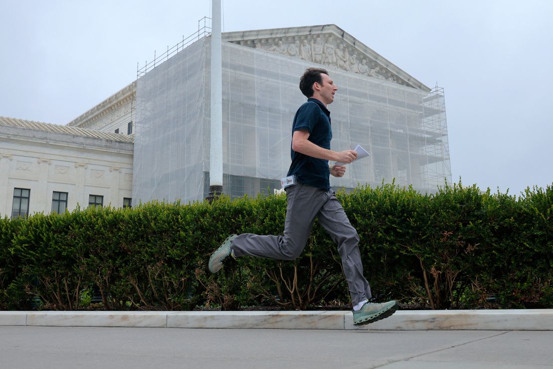 CNN's Max Rego runs out of the US Supreme Court building carrying a ruling during the last day of the court's term on June 27, in Washington, DC.