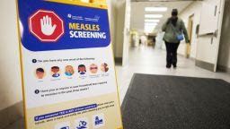 A person walks past a measles screening sign near an entrance at Victoria Hospital in London, Ontario on July 9, 2025. Canada, which officially eradicated measles in 1998, has recorded more cases of the virus this year than any other Western country, according to World Health Organization figures updated this month.