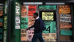 A man walks past signs displaying prices of products in US dollars at a supermarket in Caracas on September 30, 2025.