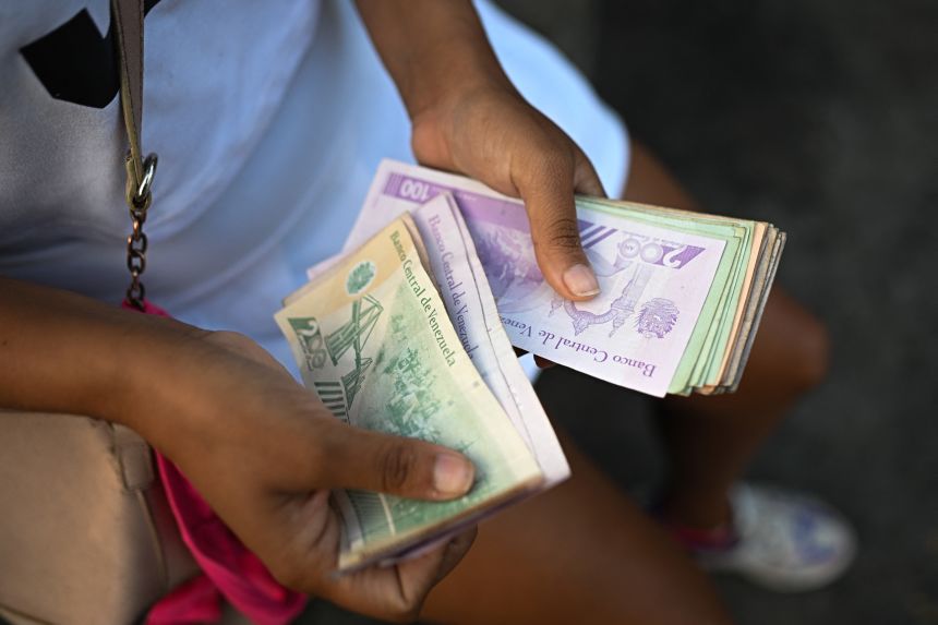 A woman counts Venezuelan bolivar banknotes to buy food at the Quinta Crespo market in Caracas on September 30.