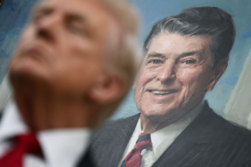 A portrait of former US President Ronald Reagan hangs behind US President Donald Trump as Trump makes an announcement in the Oval Office of the White House in Washington, DC, on September 30, 2025.