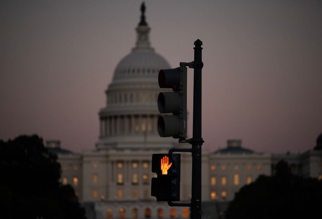 A crosswalk signal of a traffic light flashes backdropped by the US Capitol in Washington, DC, on October 1, the first day of the US federal government shutdown.