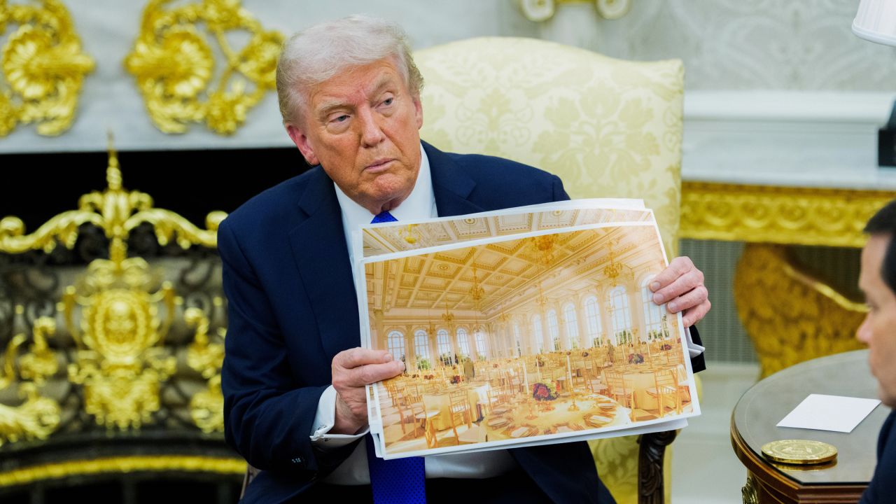 US President Donald Trump holds a rendering of the planned White House Ballroom extension during a meeting in the Oval Office on Wednesday.