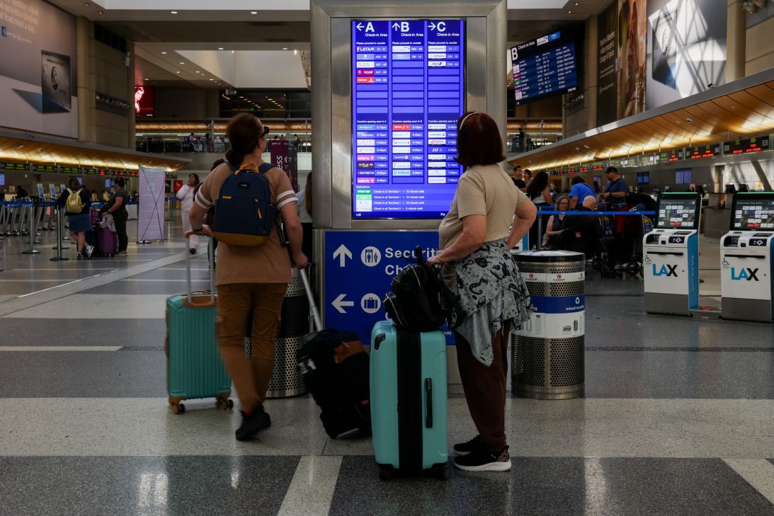 Travelers read the departure screens at Los Angeles International Airport on October 26