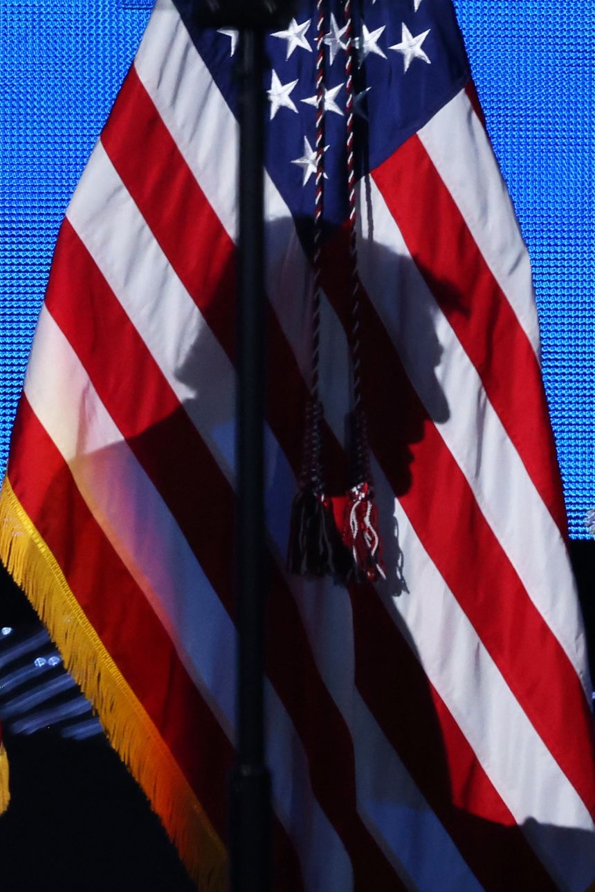 President Donald Trump's shadow is cast on the American flag as he walks on stage to address the attendees of the American Business Forum at the Kaseya Center in Miami on November 5.