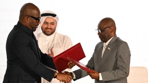 Qatar's chief negotiator Mohammed al-Khulaifi (C) observes as Sumbu Sita Mambu (L), a high representative of the head of state in the Democratic Republic of Congo (DRC) and and Rwanda-backed armed group M23 executive secretary Benjamin Mbonimpa (R) as they shake hands during the signing ceremony of the Comprehensive Peace Agreement between the DRC Government and the Congo River Alliance/March 23 Movement (AFC/M23) at the Sheraton Hotel in Doha, on November 15, 2025.