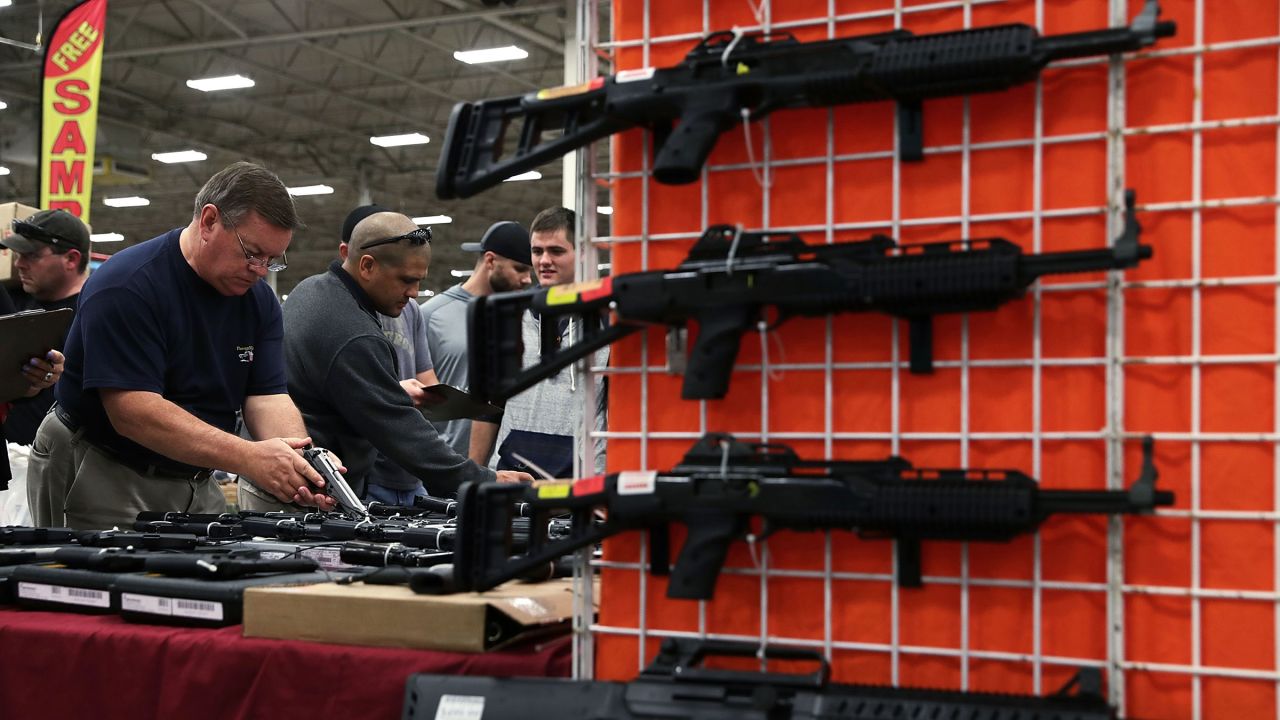 In this 2016 photo, potential buyers try out guns which are displayed on an exhibitor's table during the Nation's Gun Show at Dulles Expo Center in Chantilly, Virginia. 