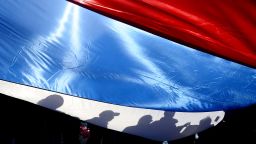 TOPSHOT - Shadows are reflected on a Russian flag as members of Russian trade unions march during a May Day rally in Saint Petersburg on May 1, 2017. (Photo by OLGA MALTSEVA / AFP) (Photo by OLGA MALTSEVA/AFP via Getty Images)
