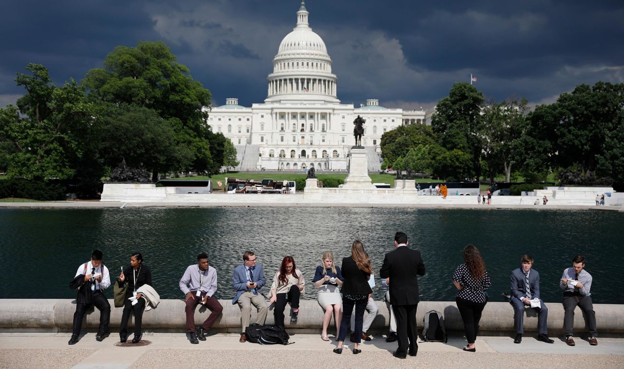 In this 2018 photo, congressional staffers eat by the reflecting pool during the 36th annual Capitol Hill ice cream party in Washington, DC.