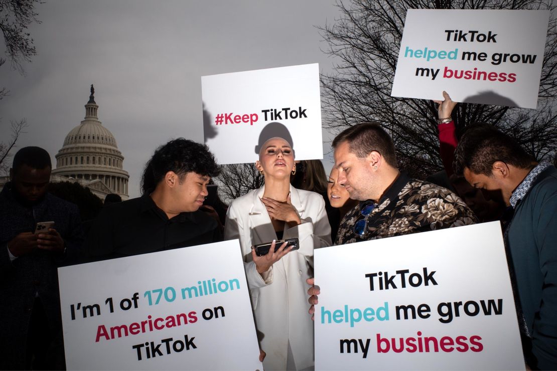 Os apoiadores do TikTok assistem ao feed da votação na Câmara enquanto se reúnem em frente ao Capitólio dos EUA em Washington, DC, em março de 2024. 