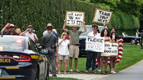 People hold signs calling for President Joe Biden to step aside this upcoming election in East Hampton, New York, as Biden's motorcade passes by on Saturday, June 29, 2024.