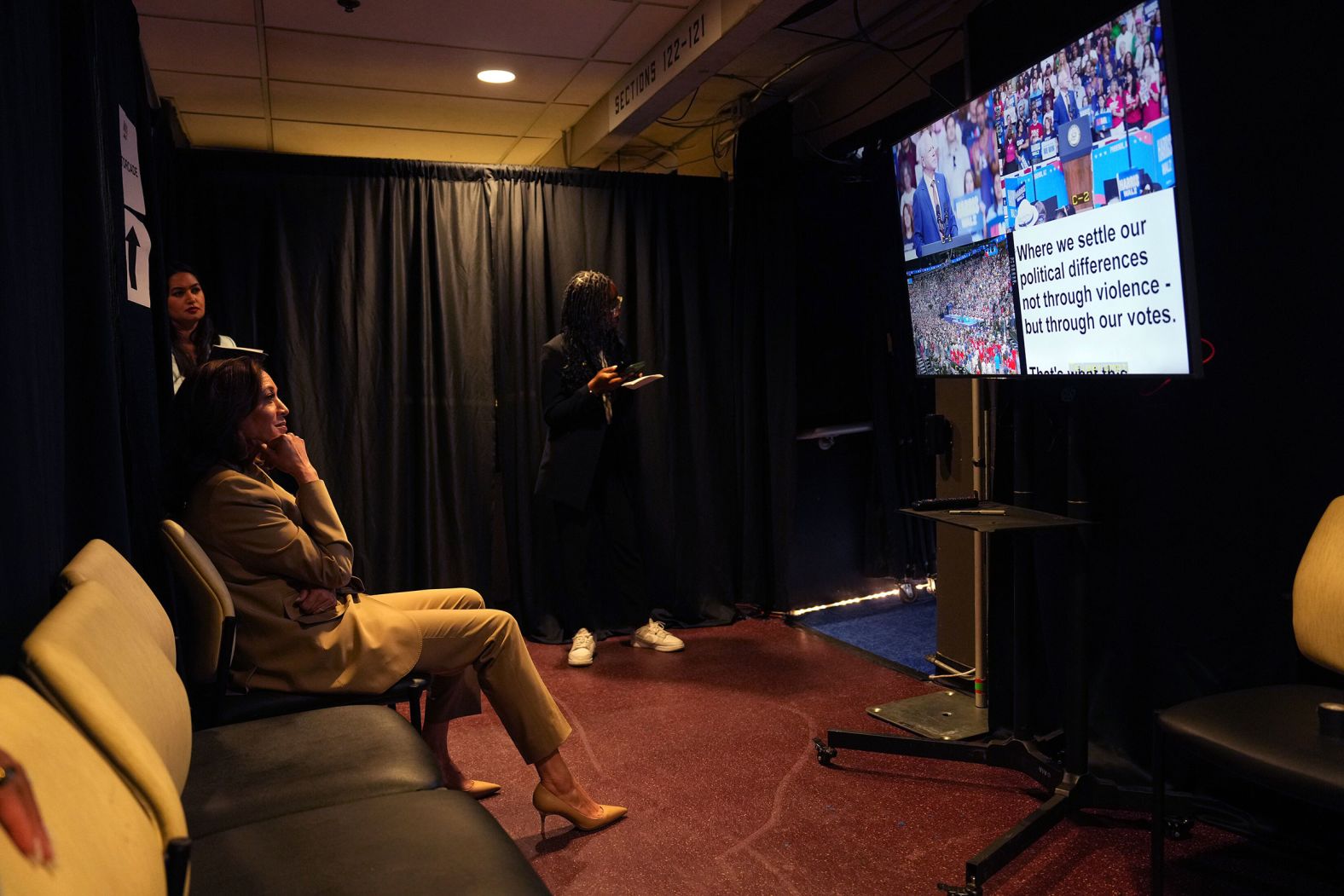 Vice President Kamala Harris and her chief of staff, Sheila Nix, watch her running mate Gov. Tim Walz of Minnesota, warming up the Glendale, Arizona crowd from backstage at their rally on August 9.