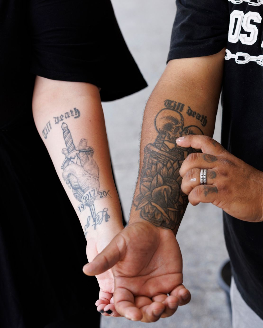 Julio and Sasha hold out matching arm tattoos the couple got when they married.