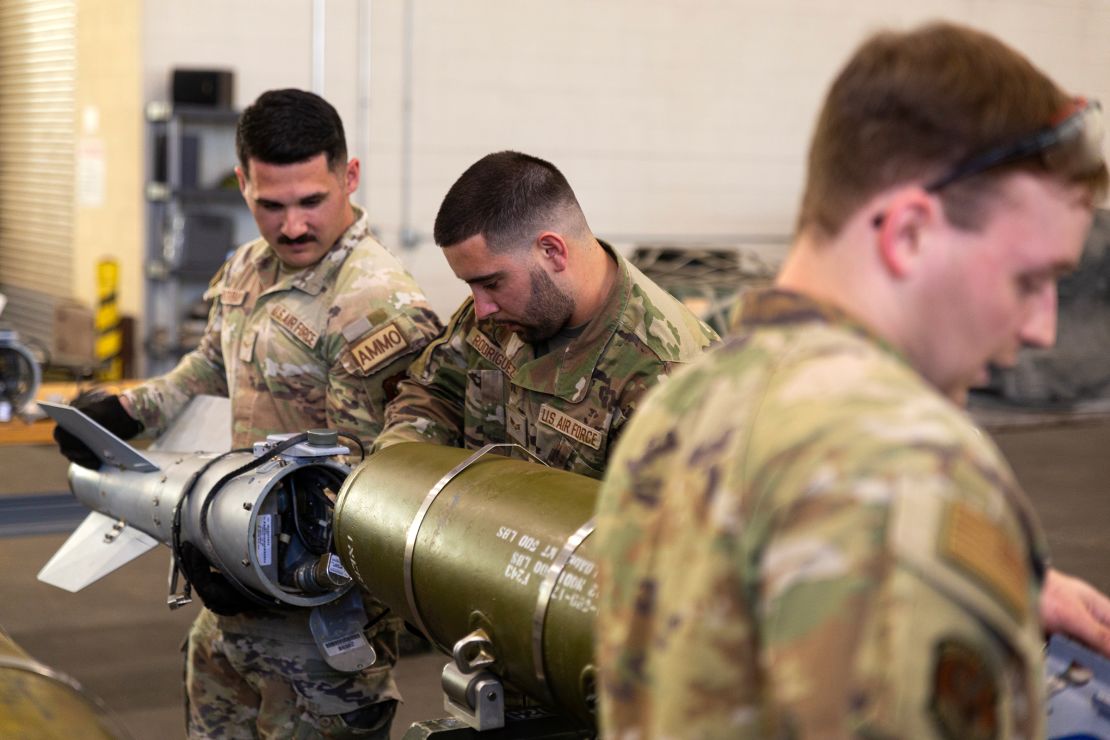 Airman Avery Bulsterbaum (left), Senior Airman Andrew Rodriguez (center), and Senior Airman Justin Joyner (right) practice assembling precision 500 pound bombs as part of the munitions teams.