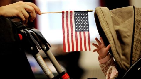 En esta foto de 2011, un bebé alcanza una bandera estadounidense durante una ceremonia de naturalización en Nueva York.