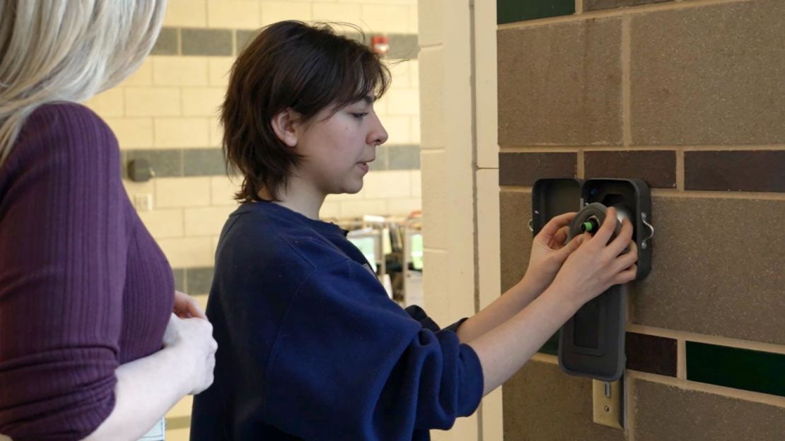 Senior Karen Mines demonstrates how to unlock a Yondr pouch, where students are expected to keep their phones during the school day, at Wakefield High School in Arlington, Virginia.