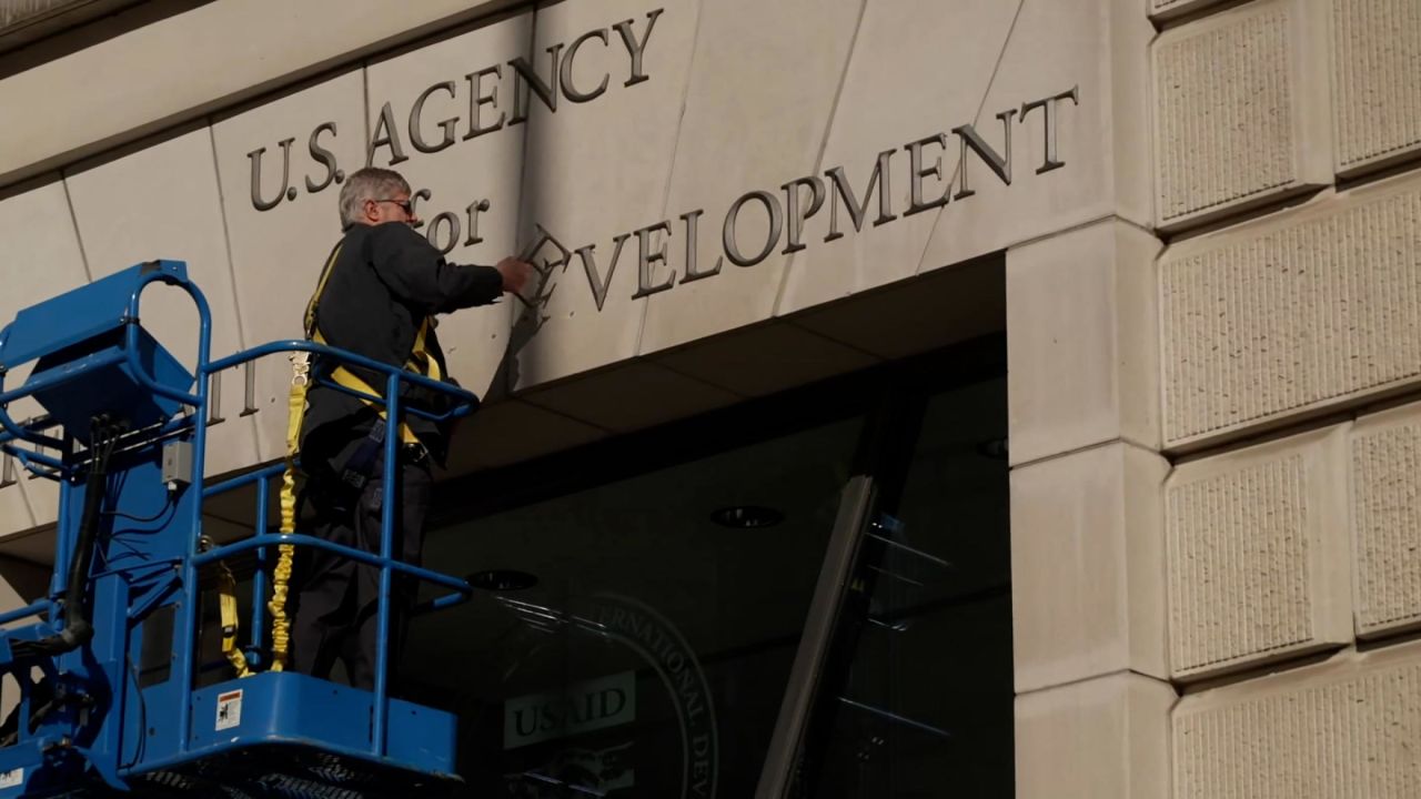 A worker removes the signage outside of the USAID headquarters in Washington, DC, on Friday.