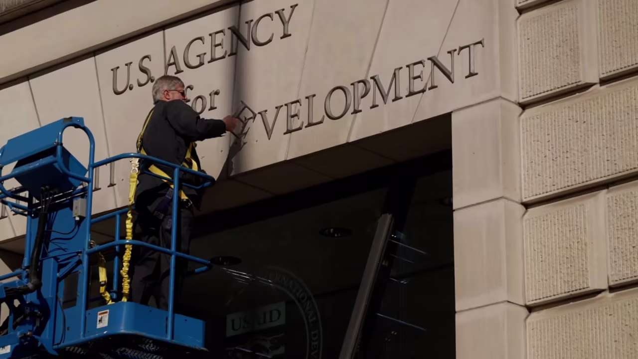 A worker removes the signage outside of the USAID headquarters in Washington, DC, on February 7.