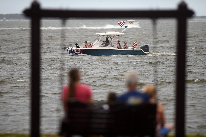 People watch boats in the "Red, White & Blue Freedom Flotilla" along the waterfront in Southport near Wilmington, North Carolina, on July 2.