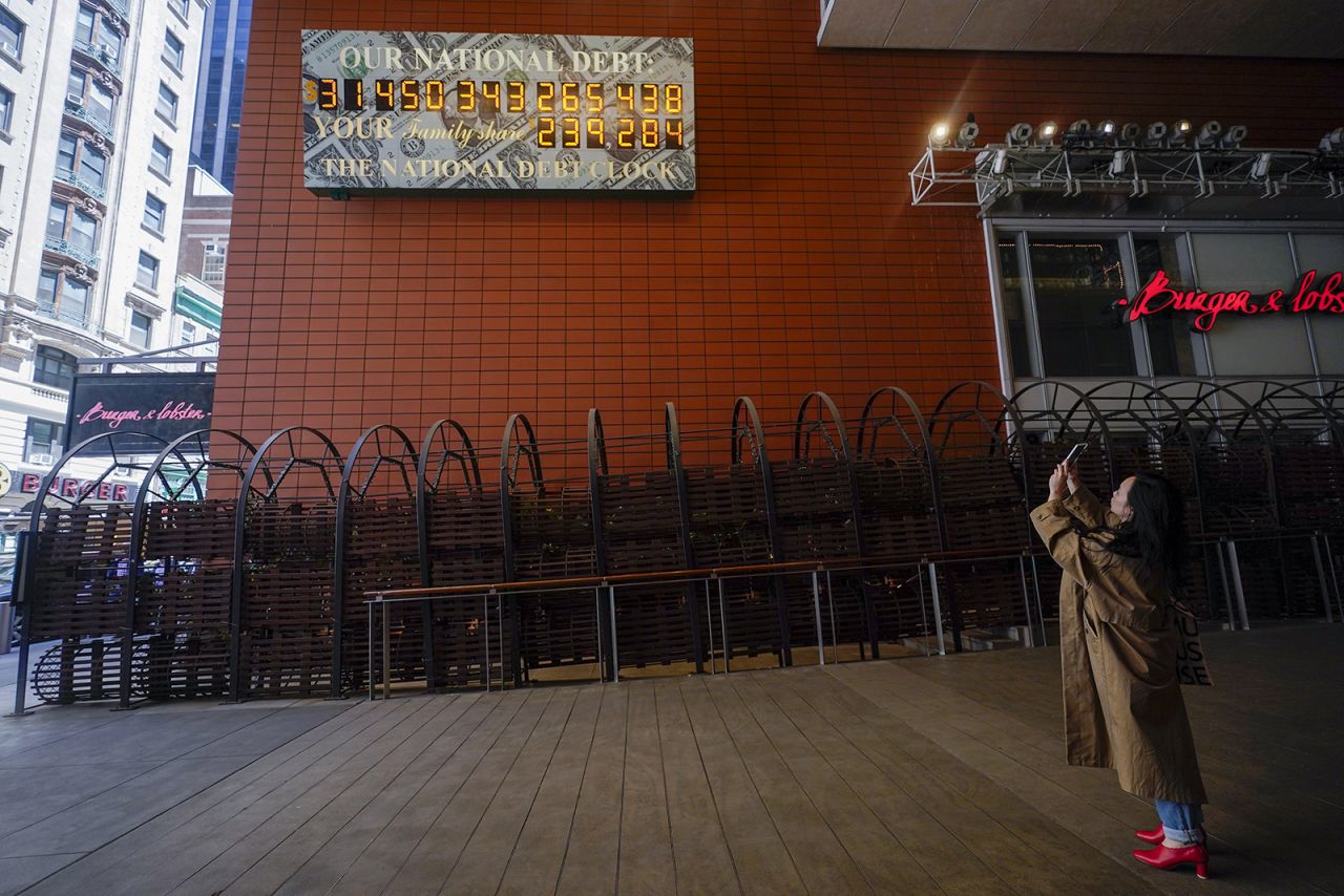 A woman stops to take a picture of the national debt clock in midtown Manhattan on May 25