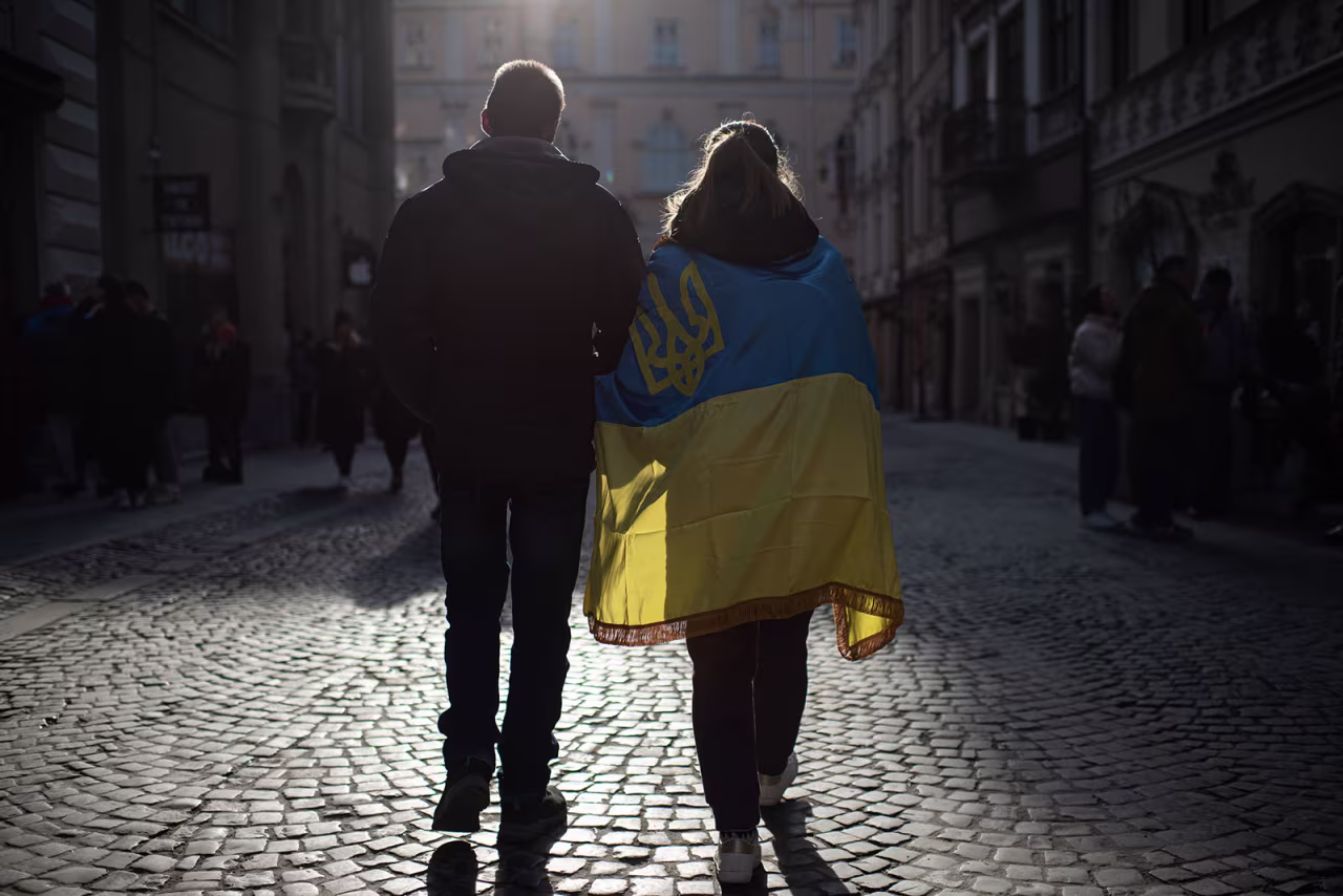 A man and a woman wrapped in the Ukrainian national flag walk the street on March 20 in Lviv.
