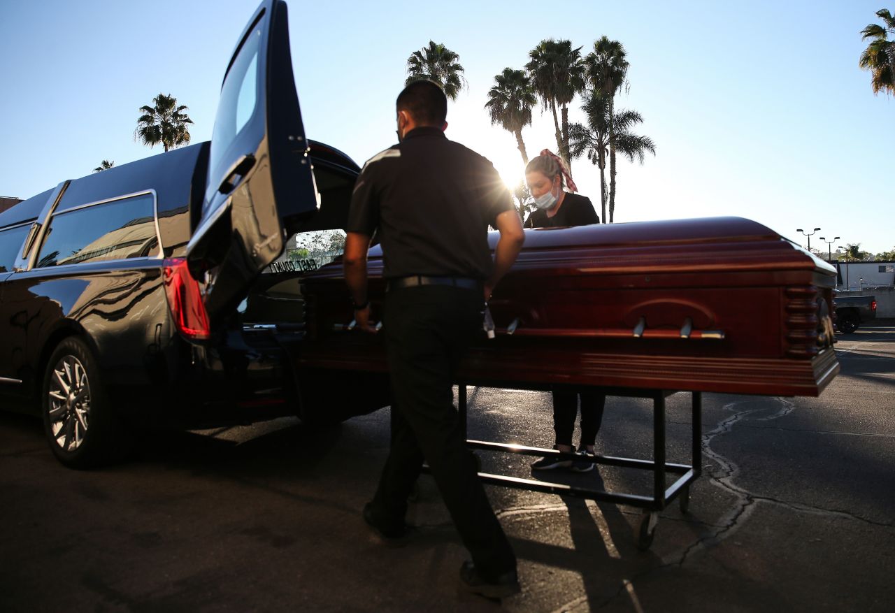 Embalmer and funeral director Kristy Oliver, right, and funeral attendant Sam Deras load into a hearse the casket of a person said to have died from Covid-19 at East County Mortuary in El Cajon, California, on January 15.