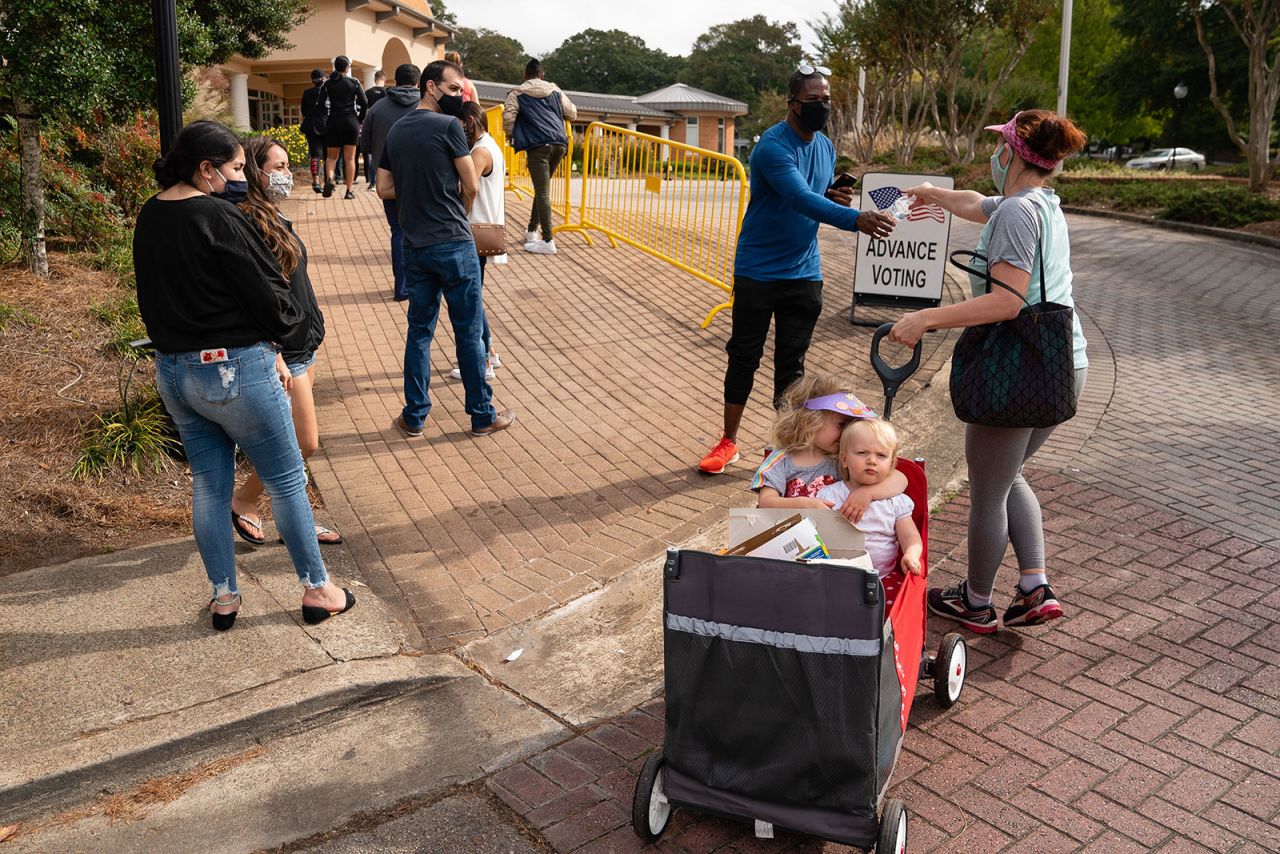 Megan Dominy, right, offers water and snacks to people waiting in line to vote in Smyrna, Georgia, in October 2020.