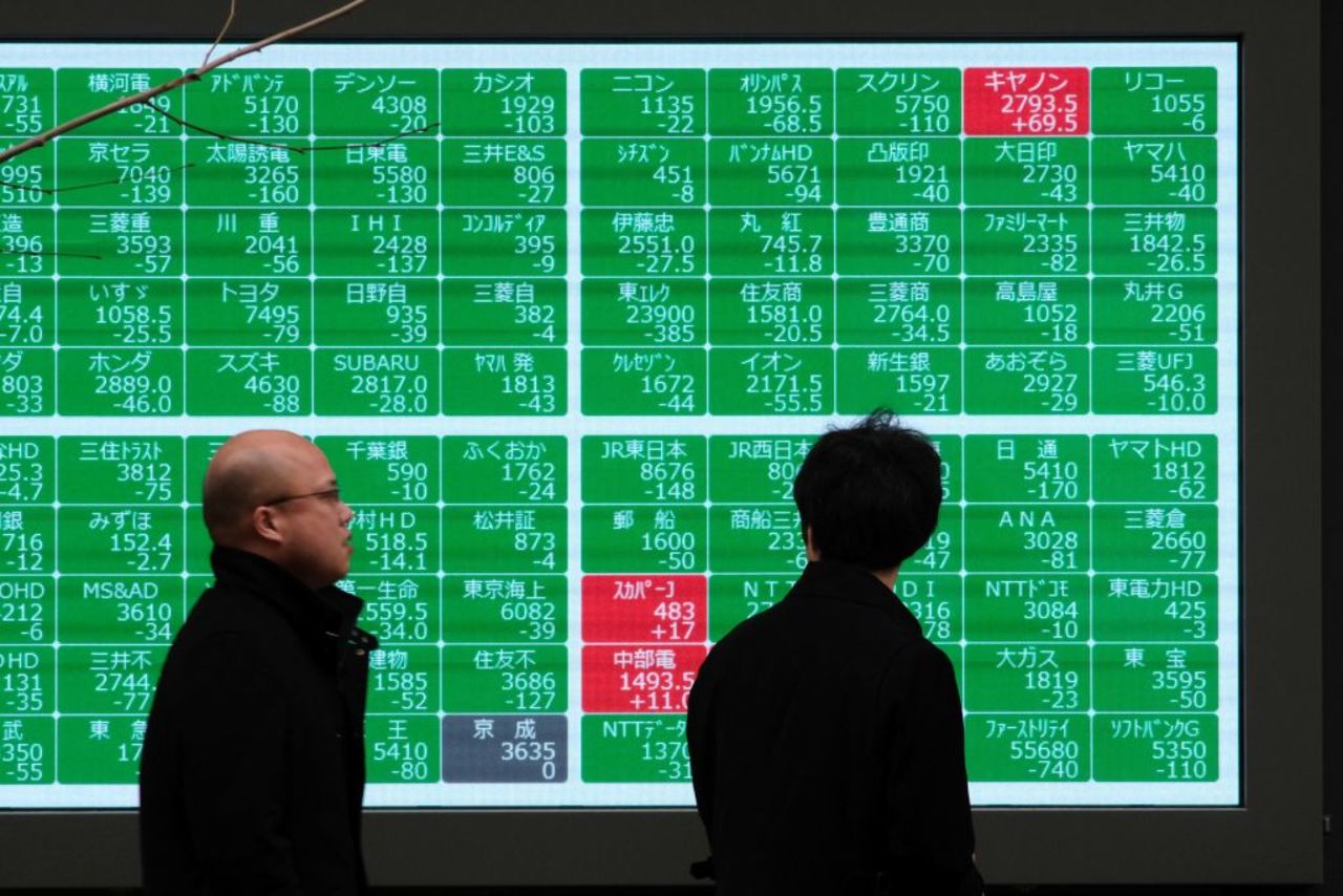 Pedestrians walk past a quotation board displaying numbers of the Nikkei 225 Index in Tokyo on Wednesday.