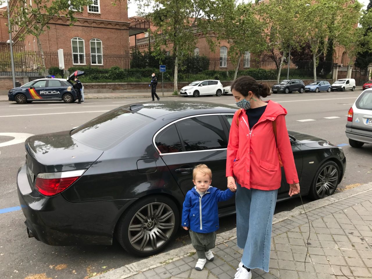 A mother who works in a financial start-up walks with her two-year-old son. Behind her is a police checkpoint, ensuring drivers comply with the lockdown.