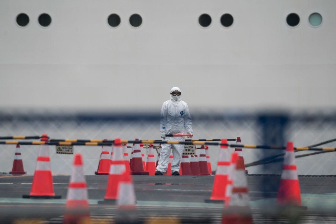 A worker wears a protective suit in front of the quarantined Diamond Princess cruise ship in Yokohama, Japan on Thursday.