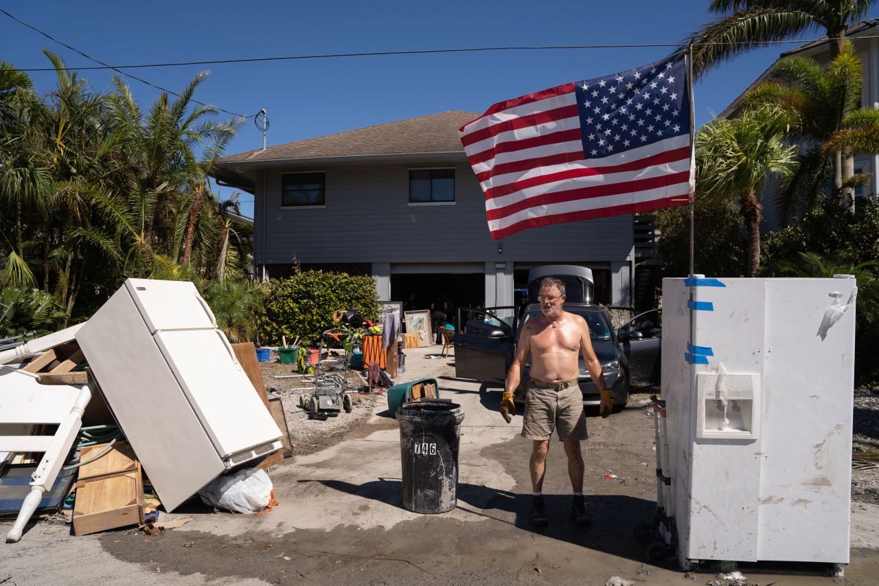 A man stands in front of a home on Sunday which was damaged by the storm surge from Hurricane Ian in Naples, Florida.