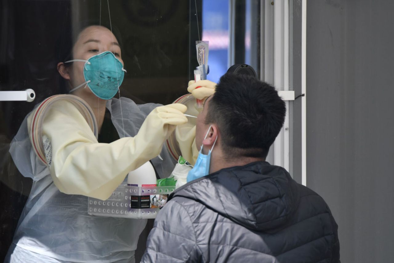 A medical staff member in a booth administers a coronavirus test at a testing station set up at Jamsil Sports Complex in Seoul on April 3. 