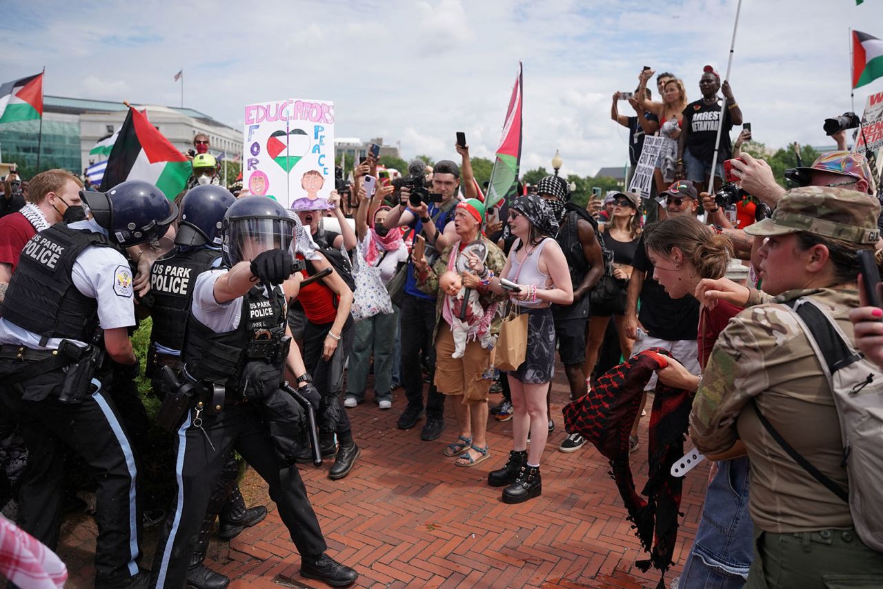 US Park Police officer gestures with pepper spray while other officers carry away a handcuffed demonstrator.