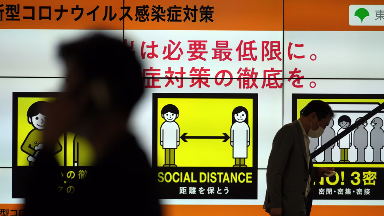 People walk past a public awareness sign for social distancing to help reduce the spread of the coronavirus Tuesday, June 22, in Tokyo.