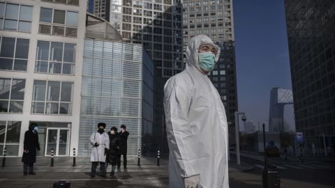 A man wears a protective suit outside an office building in Beijing on Monday, as he waits to screen people returning to work.
